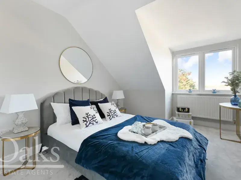 Bright bedroom with sloped ceiling and blue blanket at Byards Croft, Dion Homes.