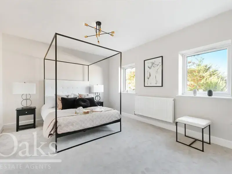 Spacious bedroom with modern four-poster bed and large window at Byards Croft, Dion Homes.