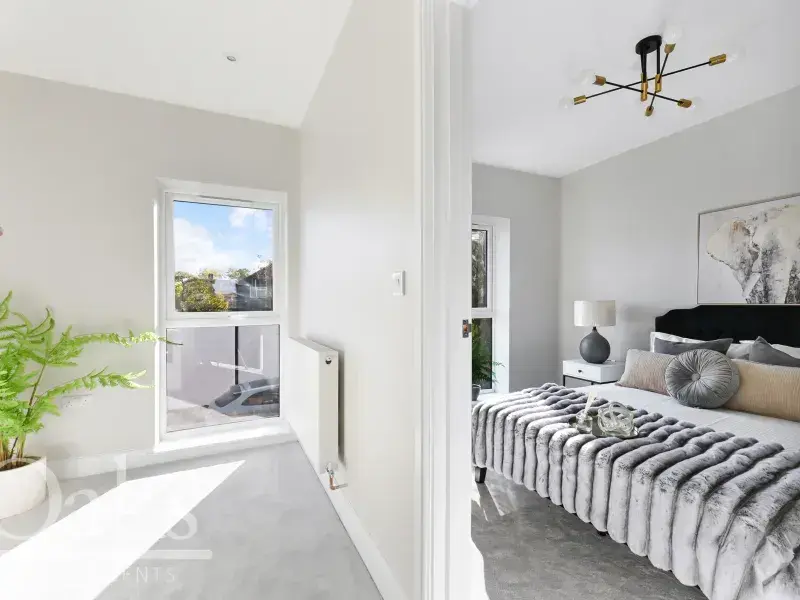 Bright bedroom with modern furniture and large window overlooking the garden, Byards Croft by Dion Homes.