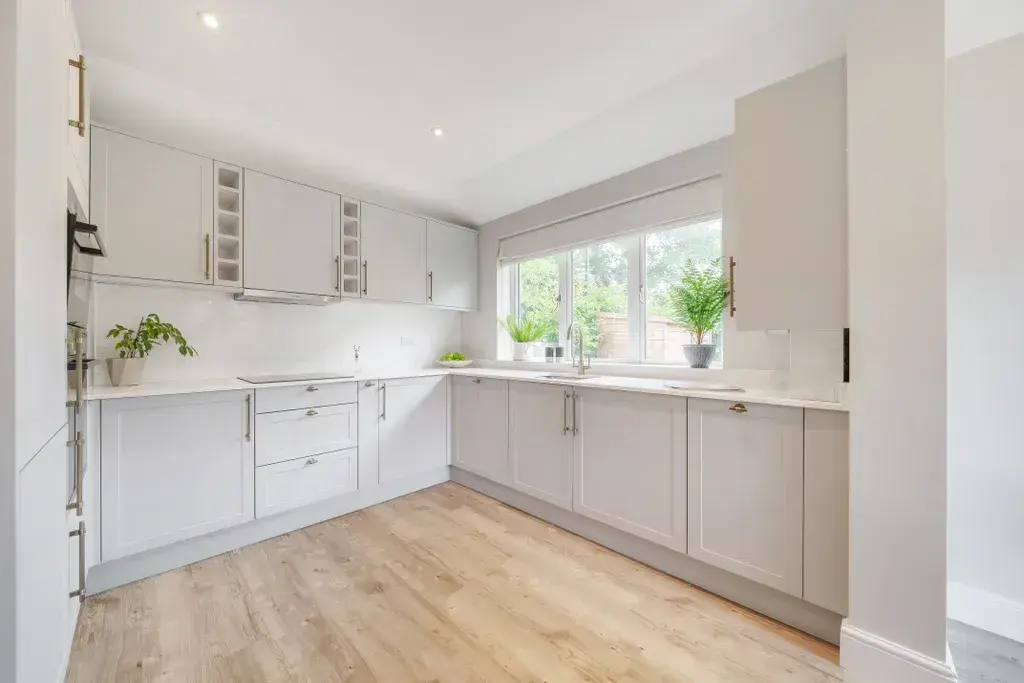 Bright shaker-style kitchen with integrated appliances and quartz worktop in a new four-bedroom house.